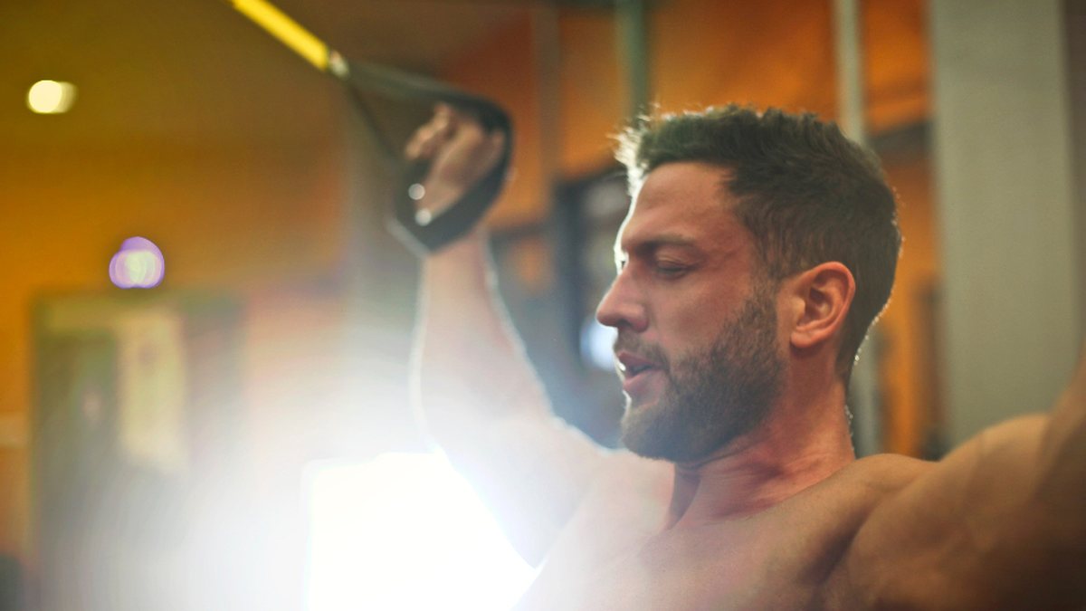 A person training in a dimly lit gym with warm backlight, mid session